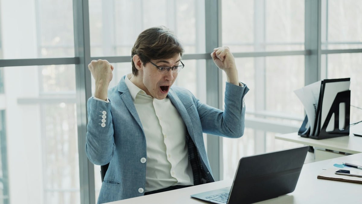 Man in suit celebrating success at office desk