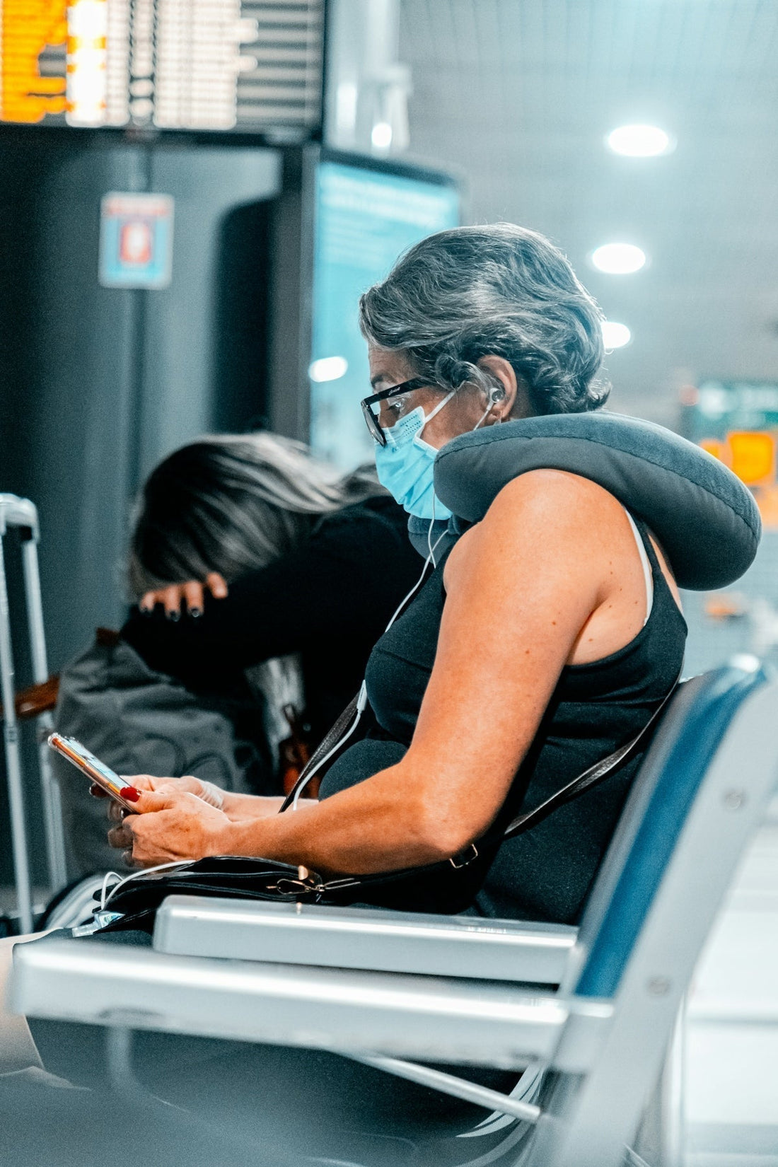 woman in blue tank top wearing white headphones holding smartphone